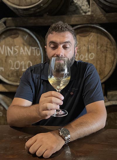 Alessio Piccioni degusta bicchiere di vino in una barricaia