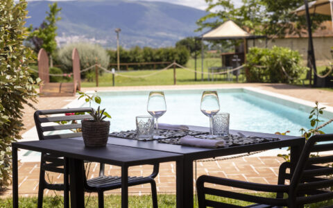 Tavolo allestito con calici e bicchieri accanto alla piscina dell'osteria favorita