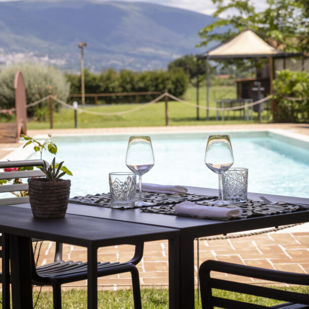 Tavolo allestito con calici e bicchieri accanto alla piscina dell'osteria favorita